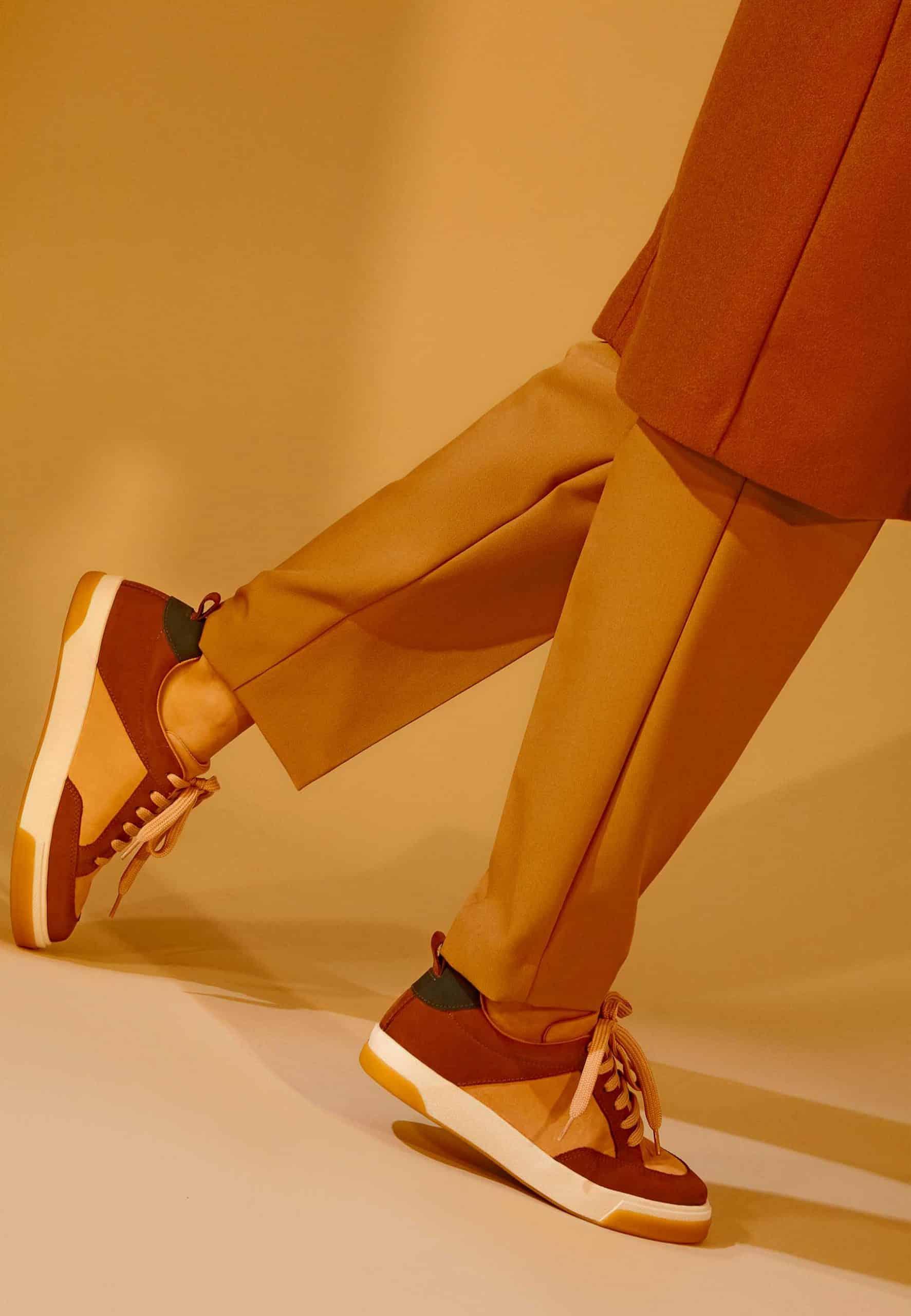 beige andira leather sneaker side view on a city sidewalk, showcasing the durable rubber sole and practical design