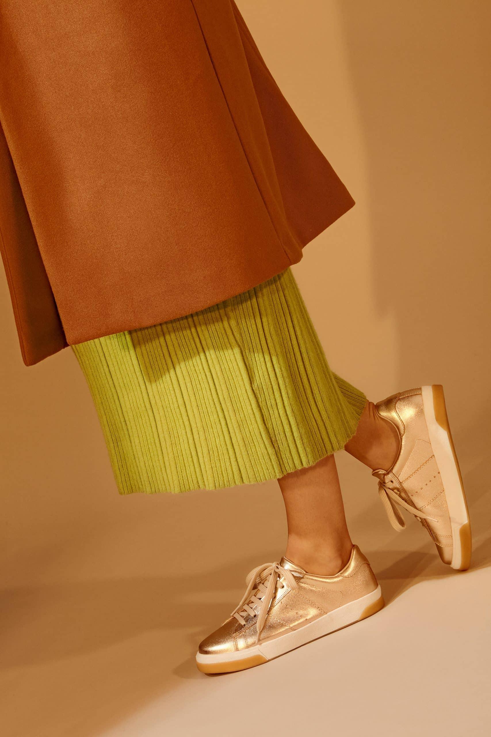 elegant golden metallic leather sneaker close-up on a marble surface, highlighting the refined texture and handcrafted details