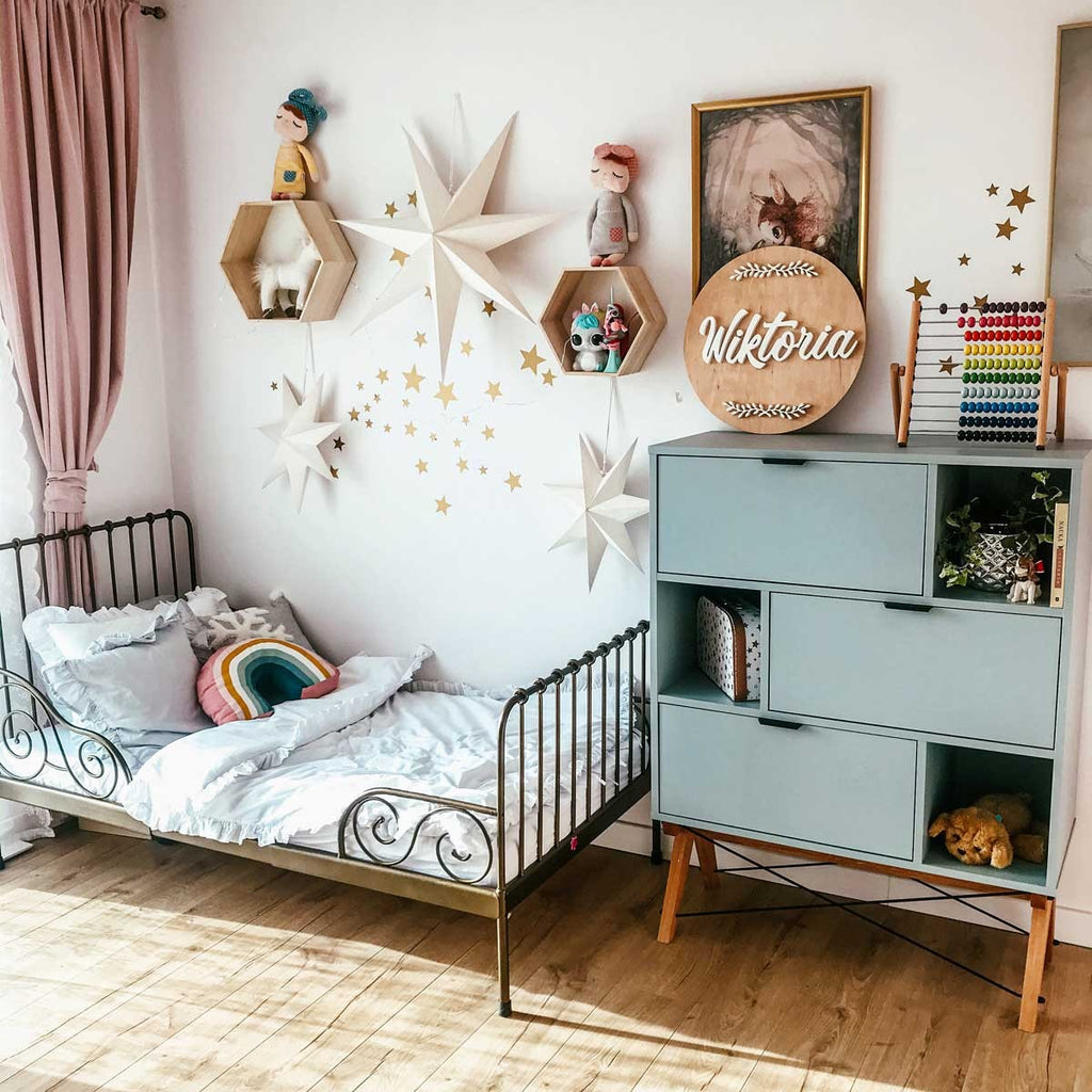 a close-up of gold star stickers on a spring-themed nursery wall, glowing in soft morning light