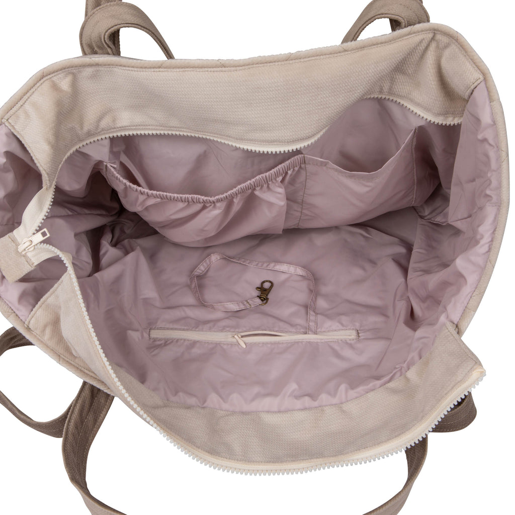 beige weekender bag on a park bench showing its adjustable strap and chic cotton texture