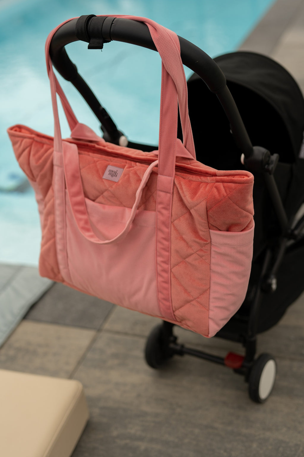 elegant pink velvet weekender bag with gold hardware, displayed on a marble surface in soft morning light