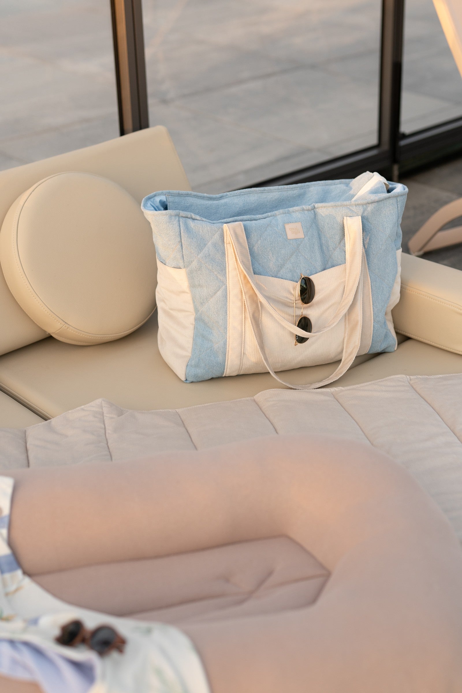 a practical denim weekender bag with multiple pockets open on a park bench