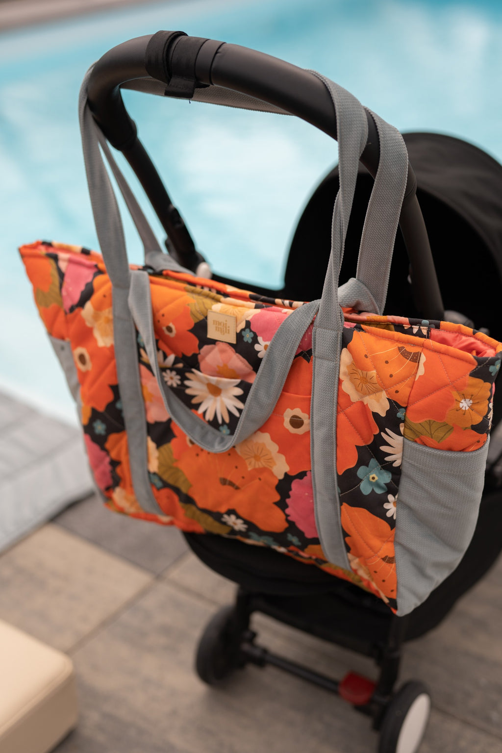 confident mom holding a spacious floral weekender bag with multiple pockets