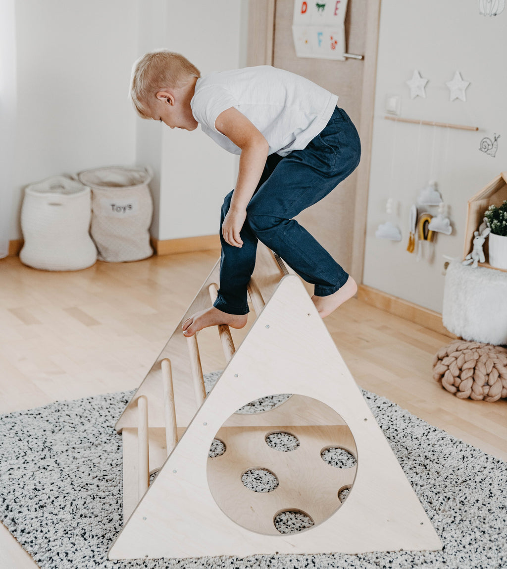 a soft-lit view of a toddler safely exploring the gentle angles of a birch plywood montessori climber