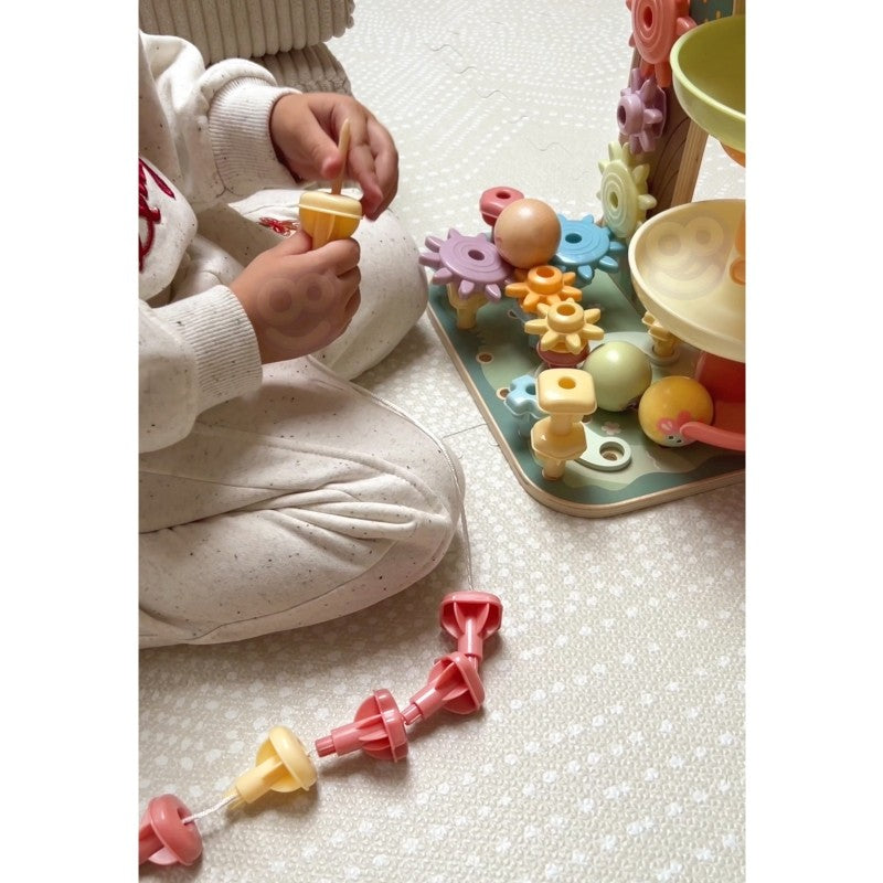montessori activity tree with spinning gears and bead maze in warm natural light