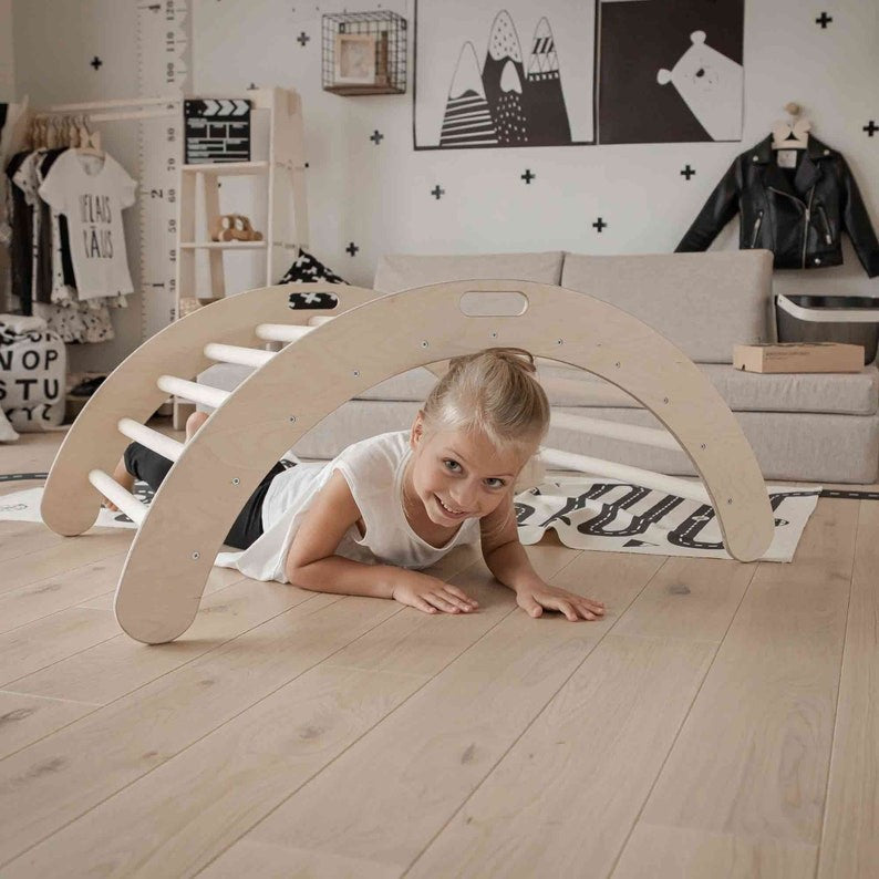 a child laughing while rocking on the montessori climbing arch turned balance board