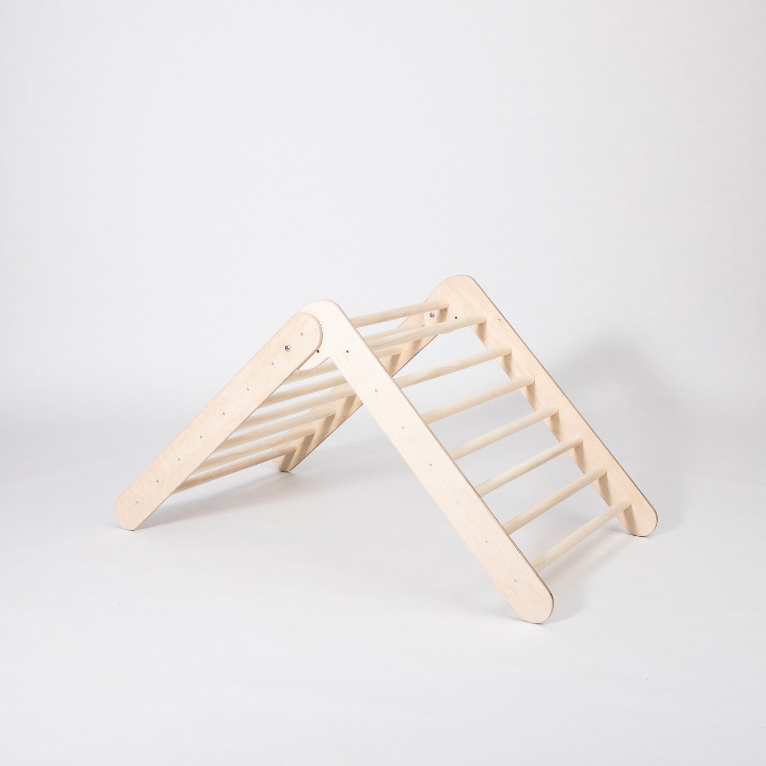 a child's hand gripping the sturdy birch rungs of a foldable montessori climbing triangle
