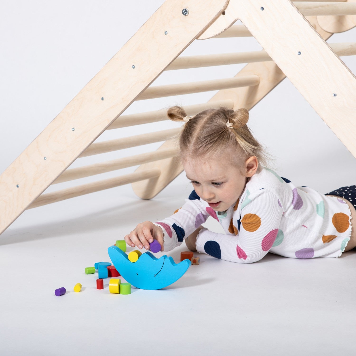 a toddler's gleeful hands reaching for the top rung of a birch plywood climbing triangle