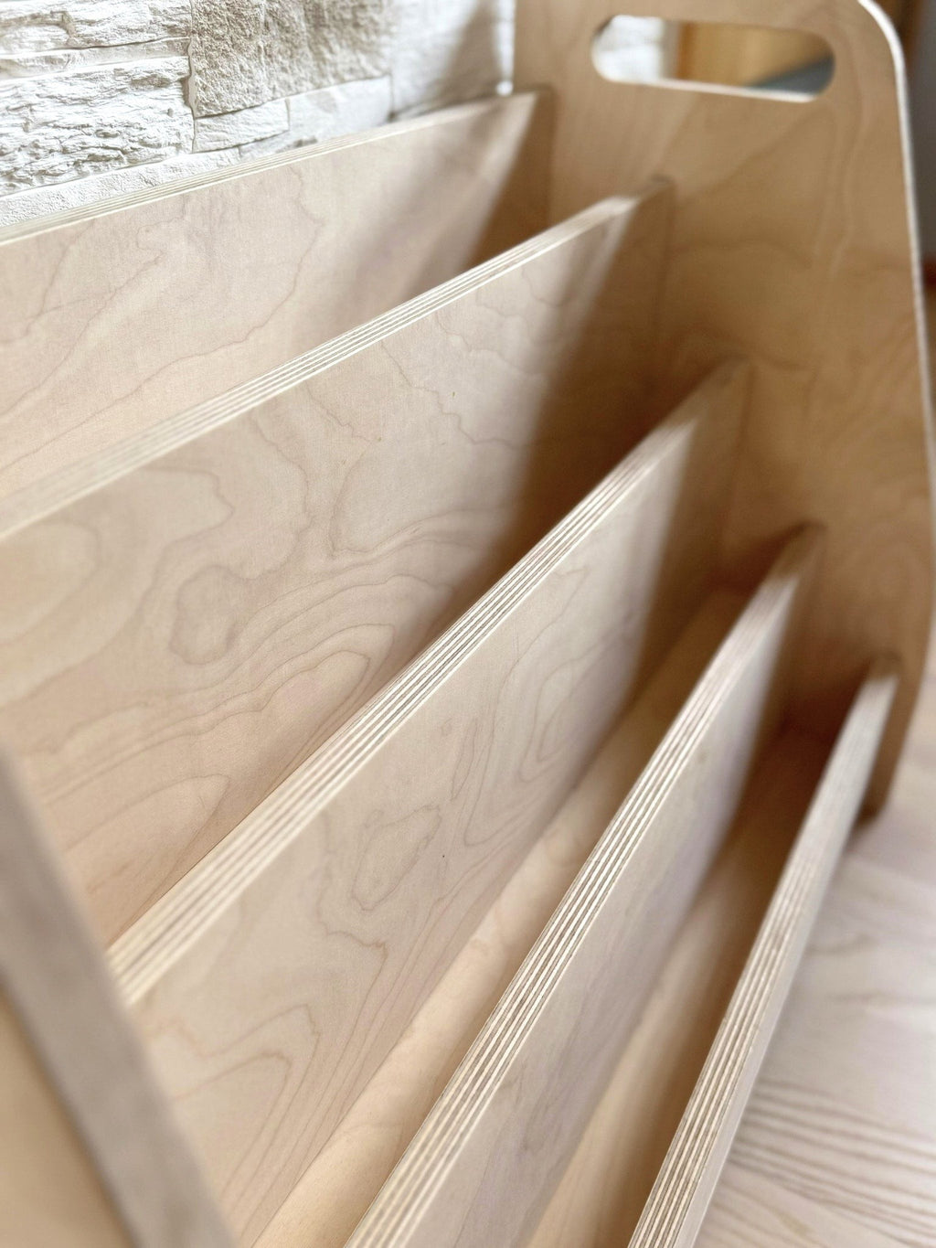 a soft-lit montessori book stand in a cozy reading nook with birch wood grain
