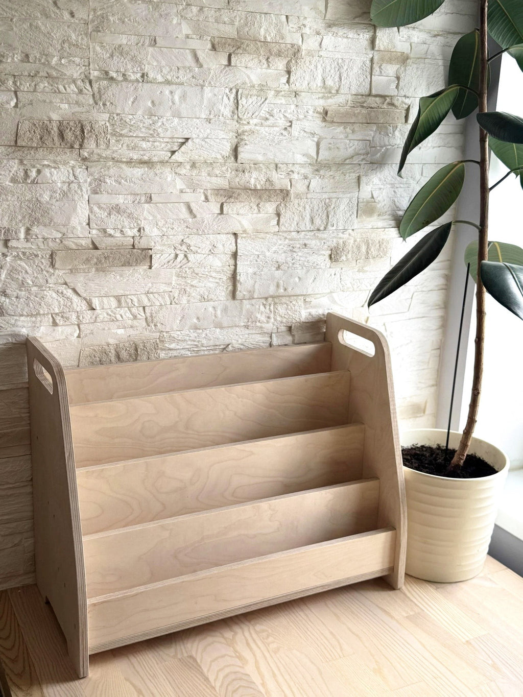 a functional kids book stand with four tiers of front-facing books in a bright reading nook