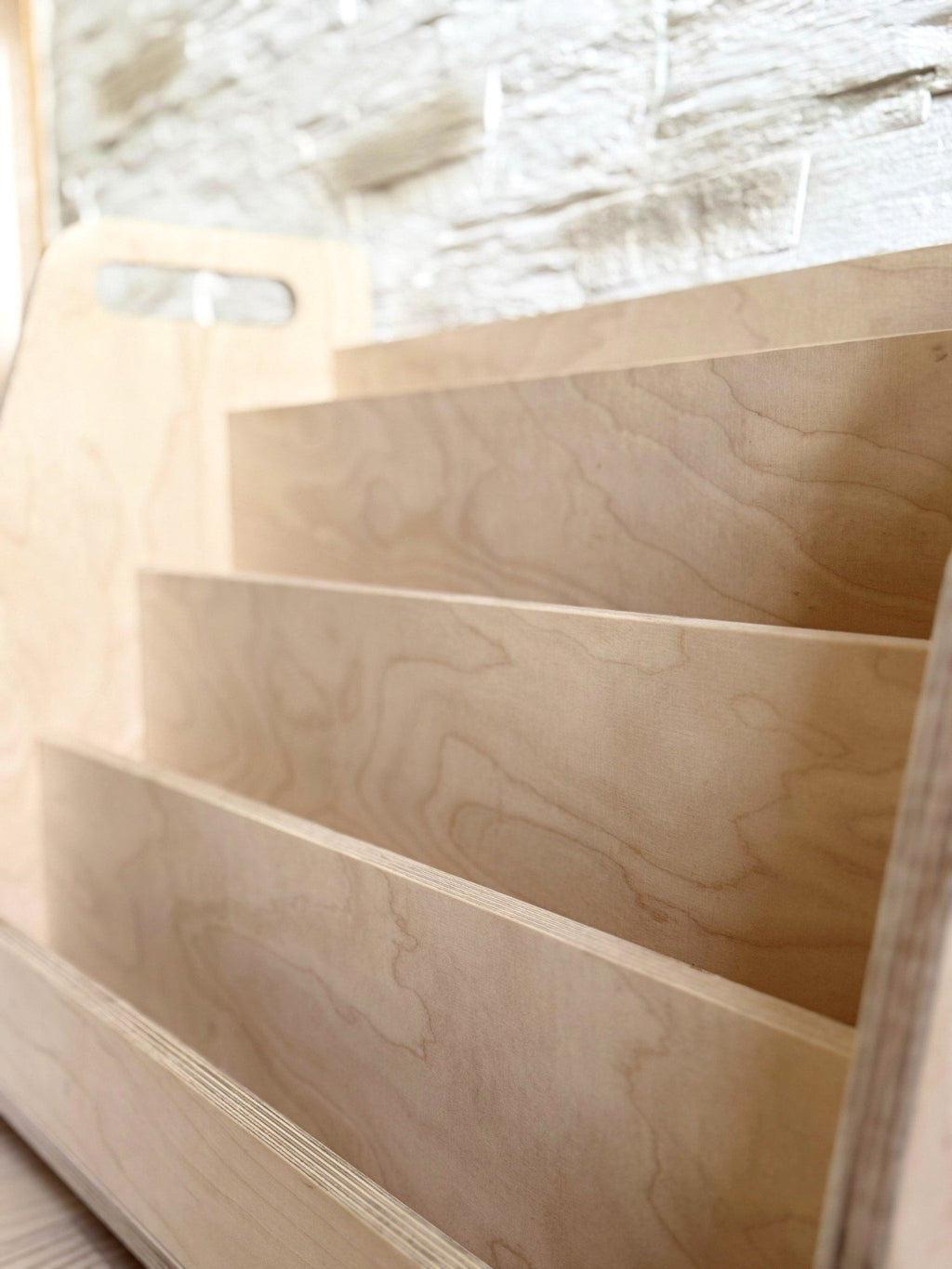 a playful child's hand selecting a colorful book from the wooden display shelf