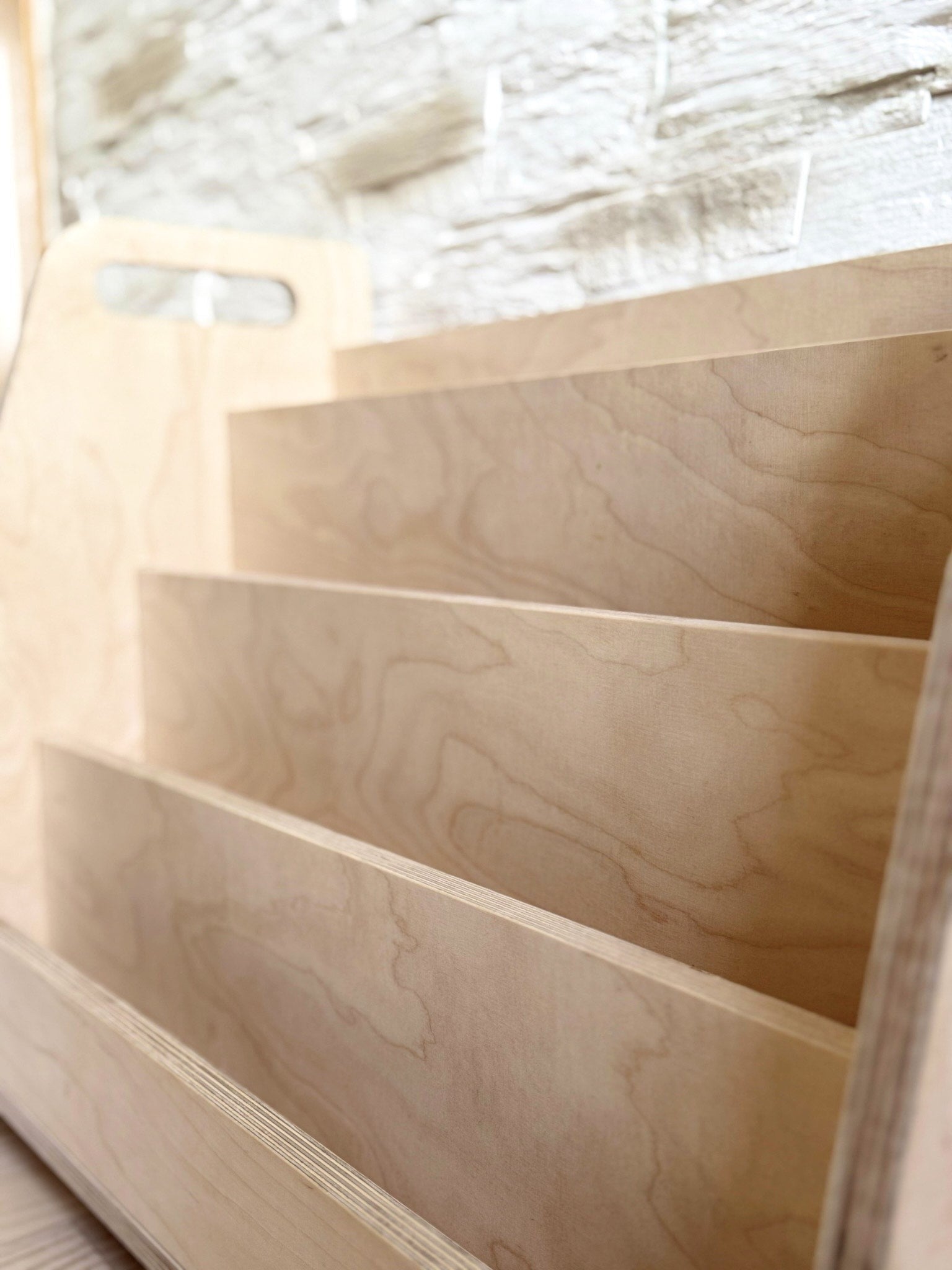 a playful child's hand selecting a colorful book from the wooden display shelf