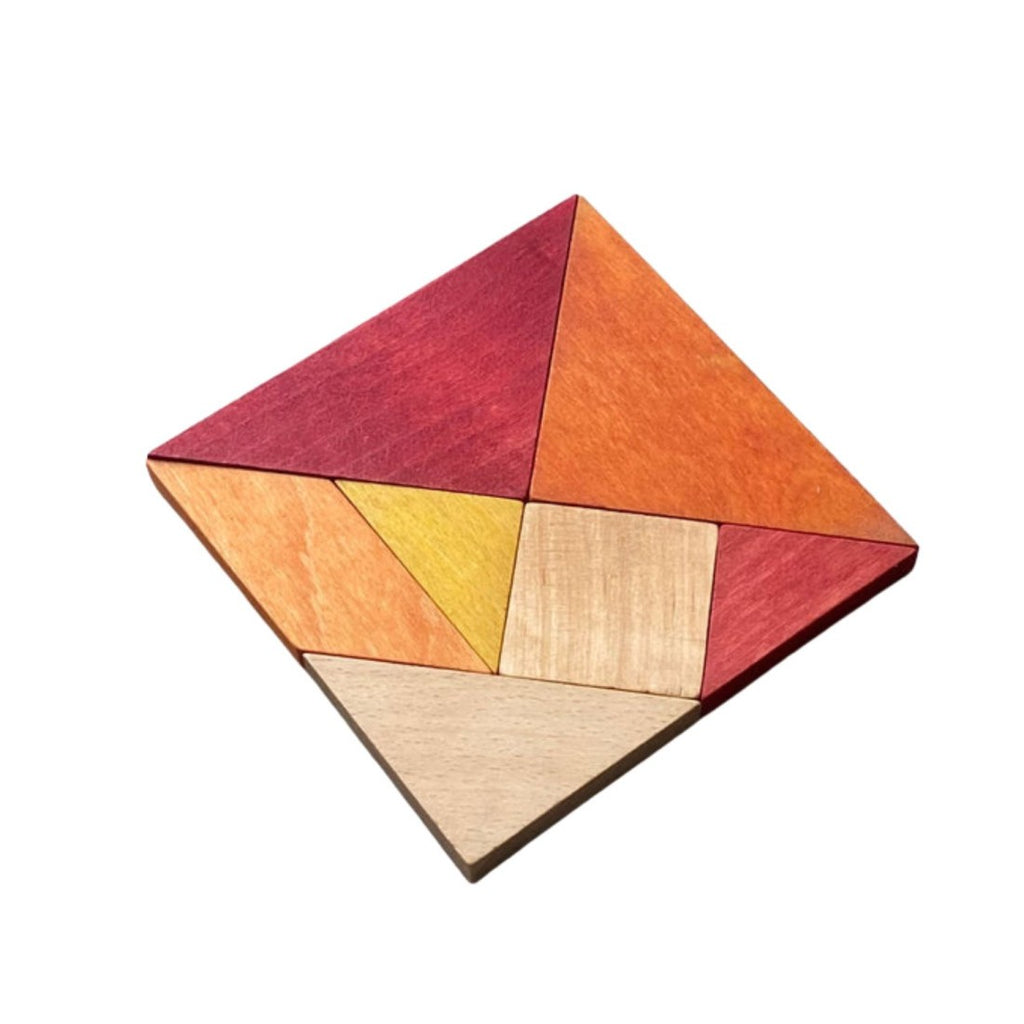 a close-up of warm-toned wooden tangram pieces arranged into a swan on a rustic wooden table