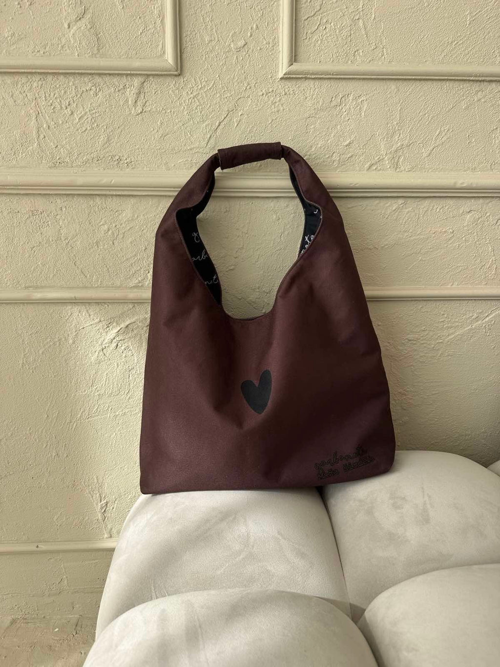 a playful brown moon bag heart held by a woman laughing in a sunlit park