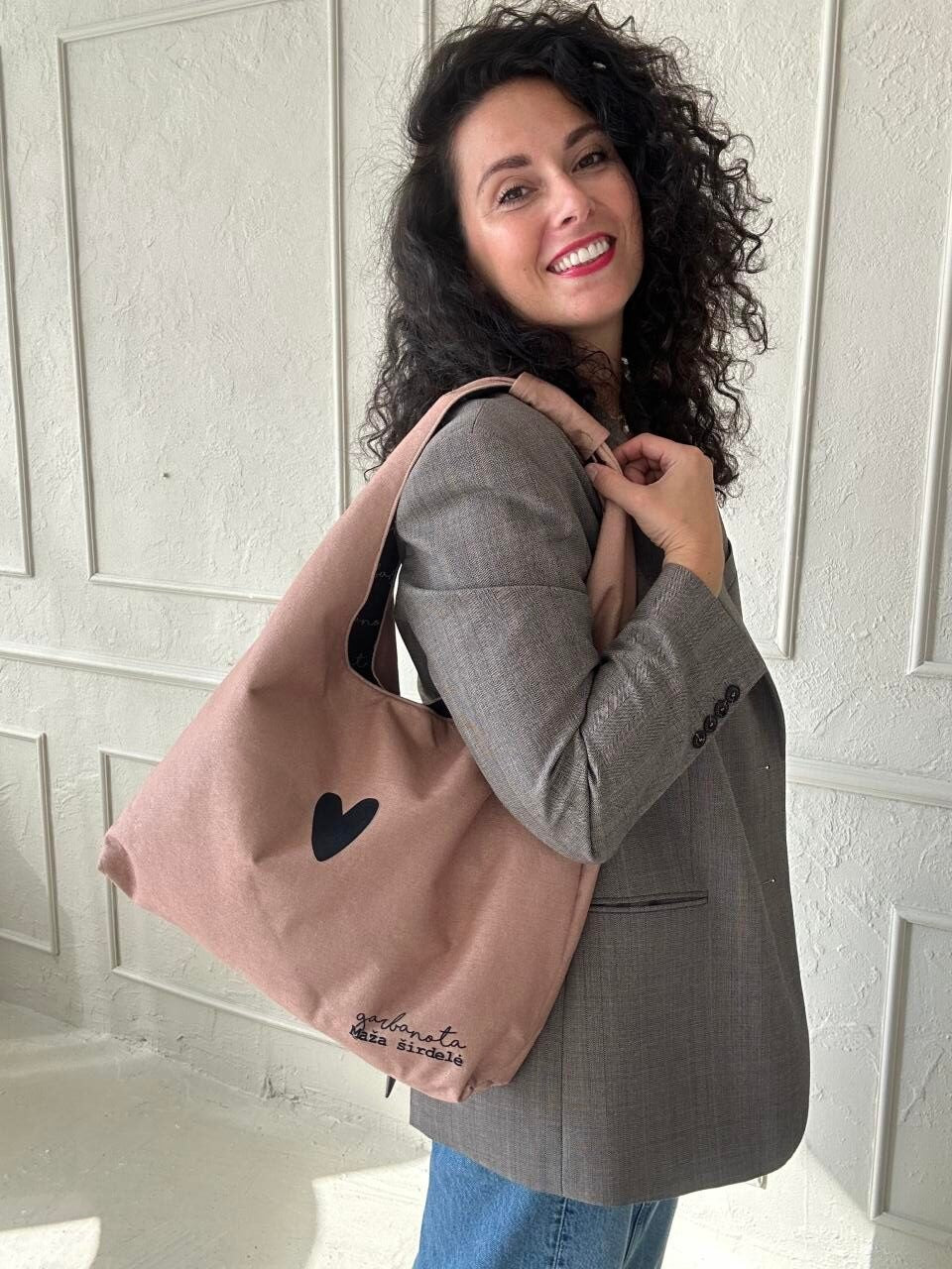 bold cream moon bag heart on a model, showcasing its chic shape and unique garbanota lining