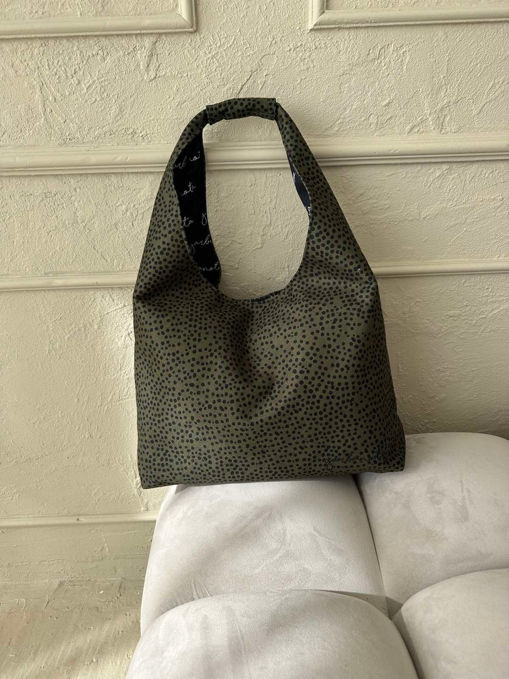 playful khaki polka dot moon bag heart held against a sunny backdrop, showing its spacious and fun hobo shape