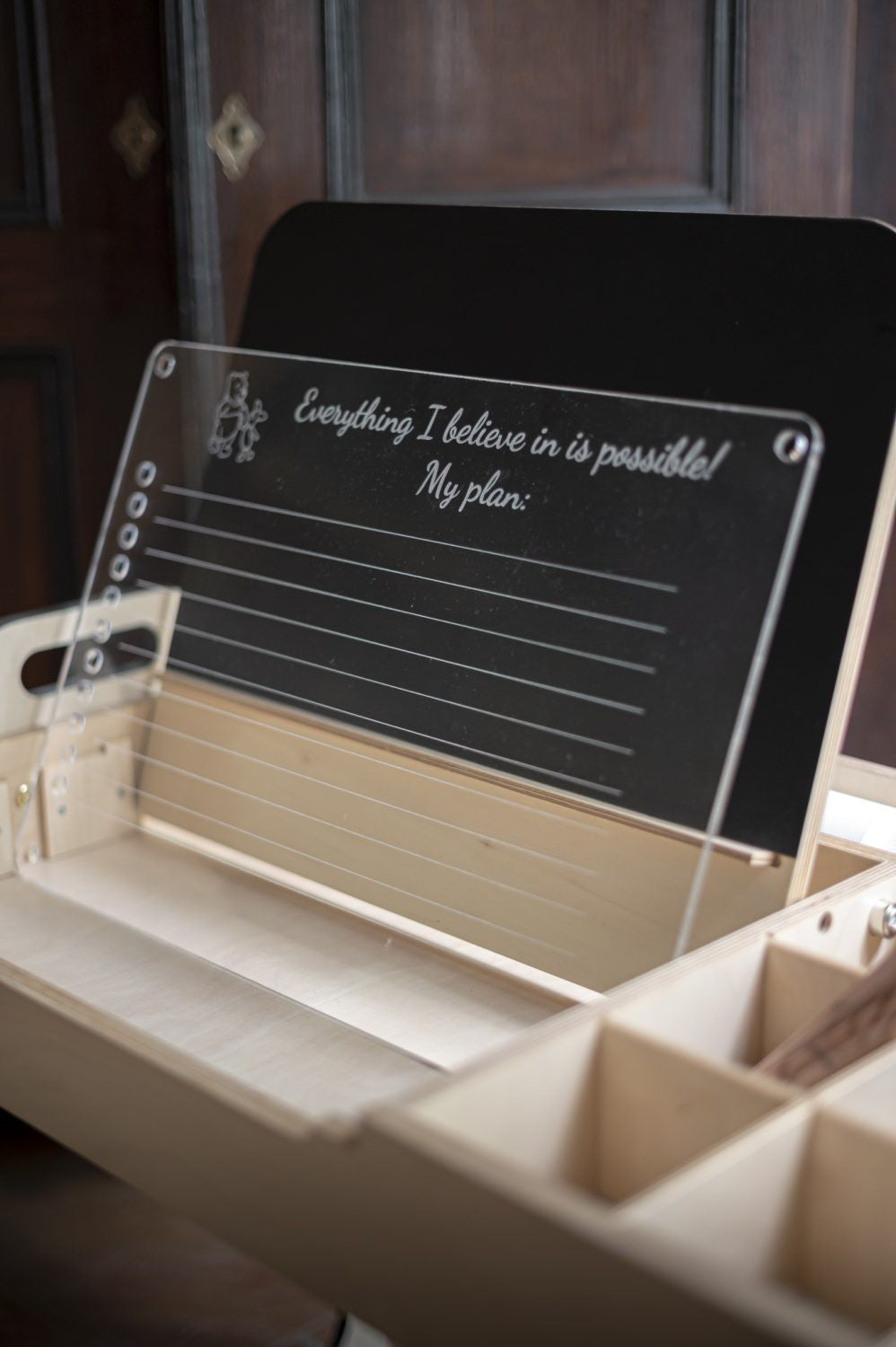 a young child drawing on the julle art table with natural birch plywood grain visible