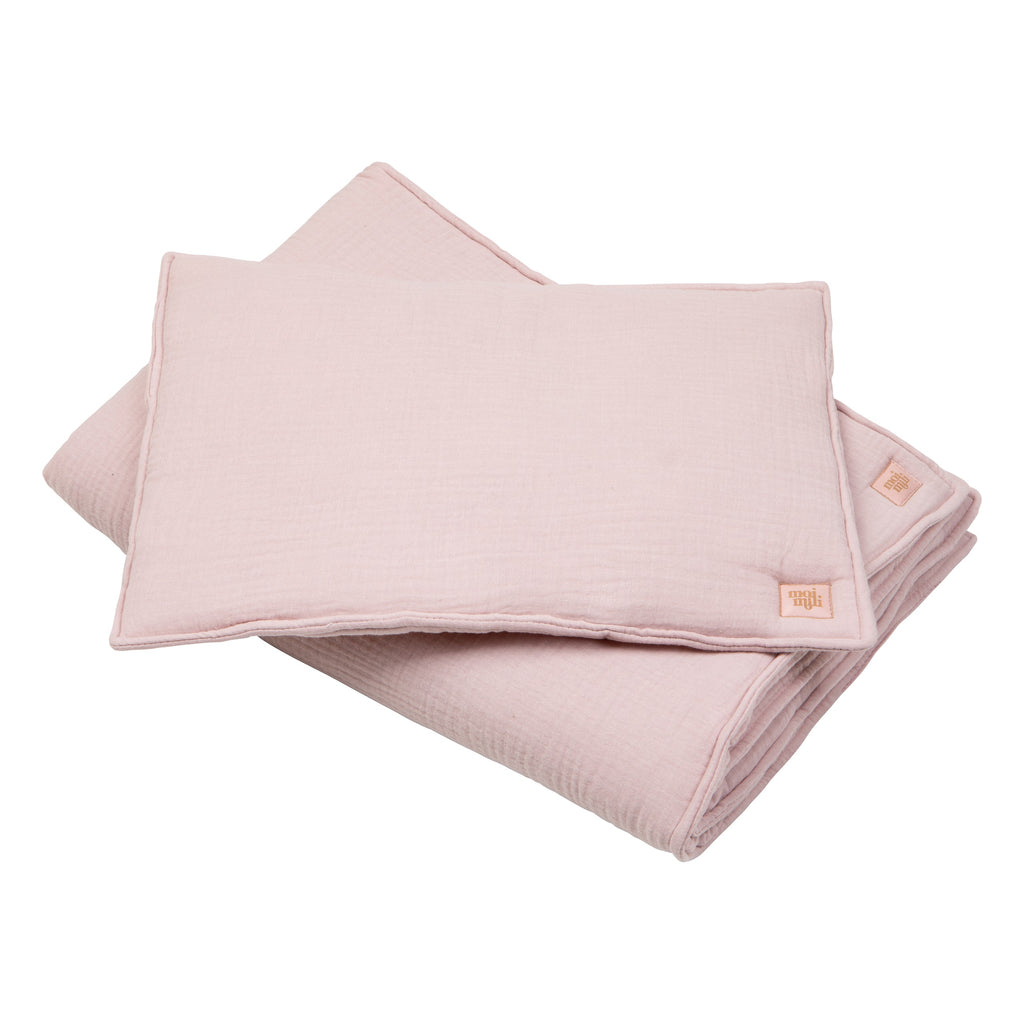 gentle baby pink muslin blanket and pillow set on a soft, sunlit nursery chair