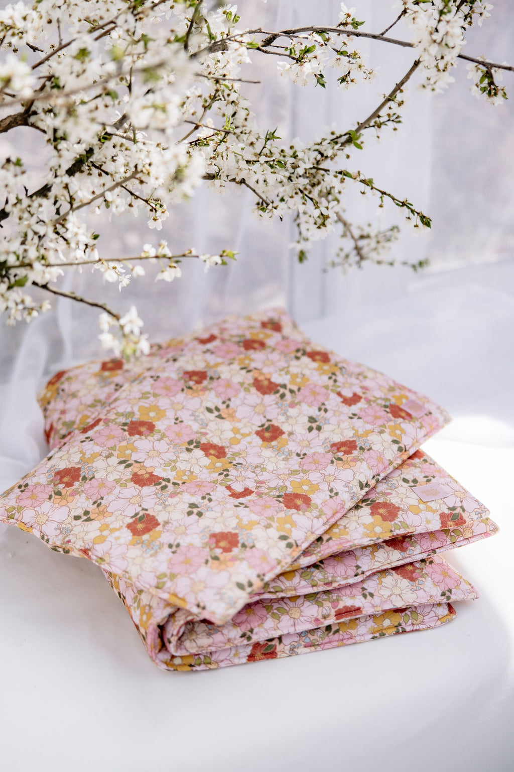 soft muslin baby pillow resting on a spring garden blanket in gentle morning light