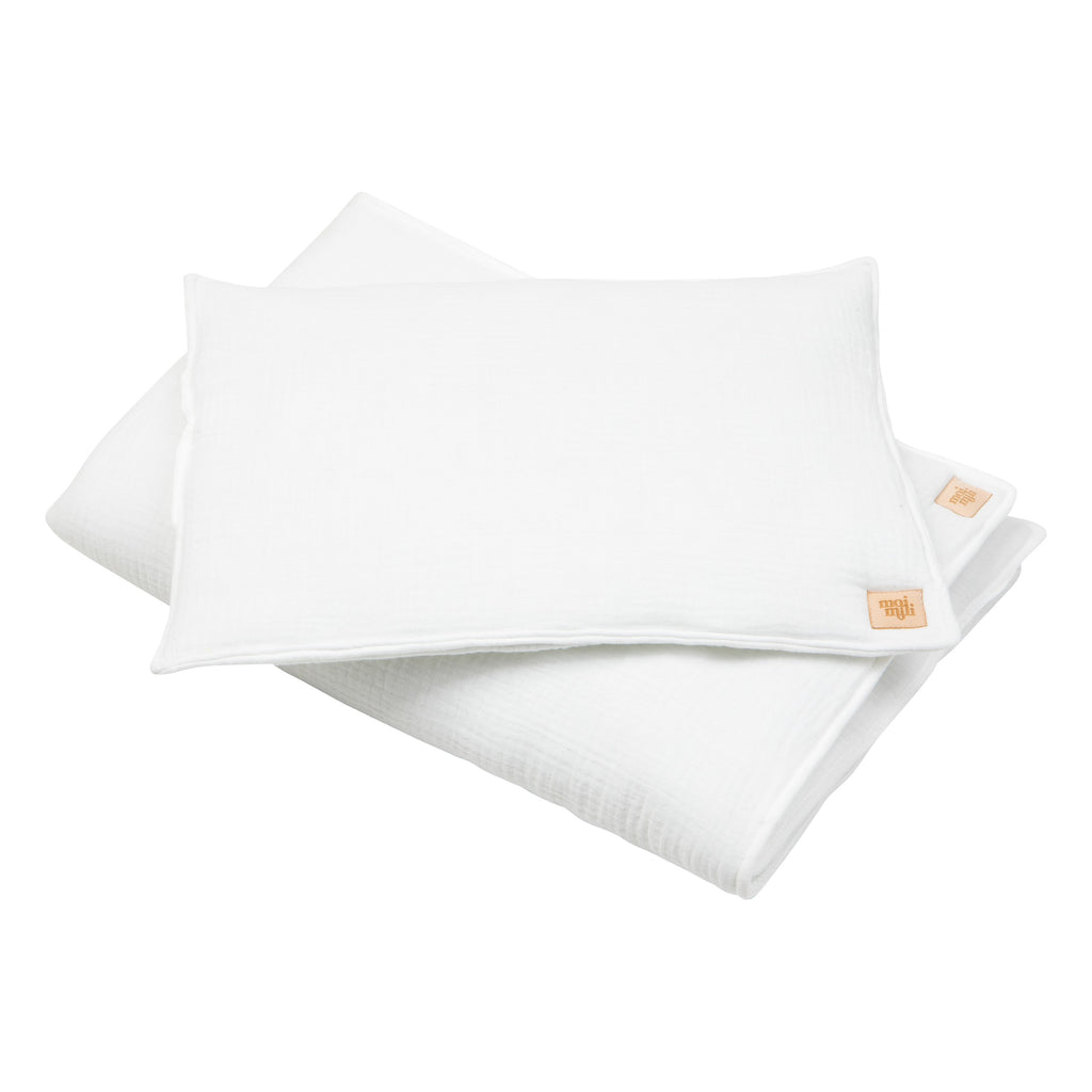 elegant cream muslin baby blanket and pillow set draped over a wooden cradle, soft light highlighting the delicate texture