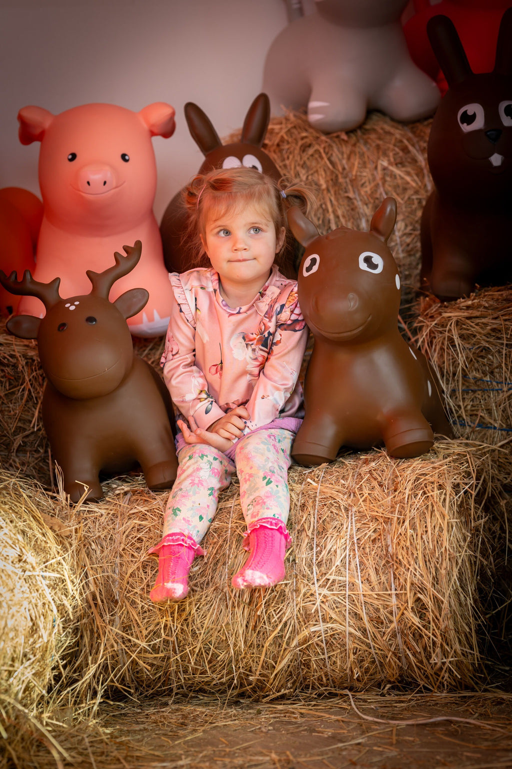 a toddler laughing while bouncing on a brown horse hopper toy in a sunny garden