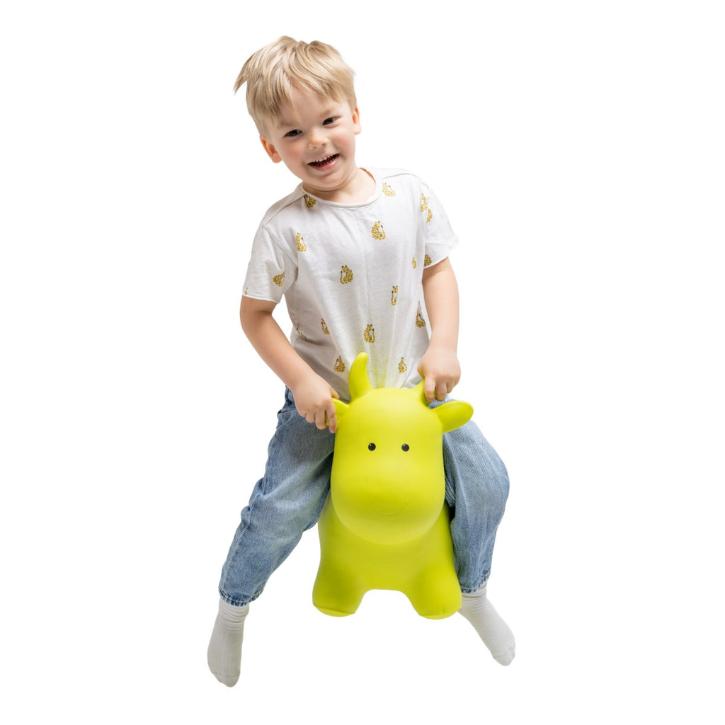 confident toddler bouncing on a vibrant green cow hopper toy indoors