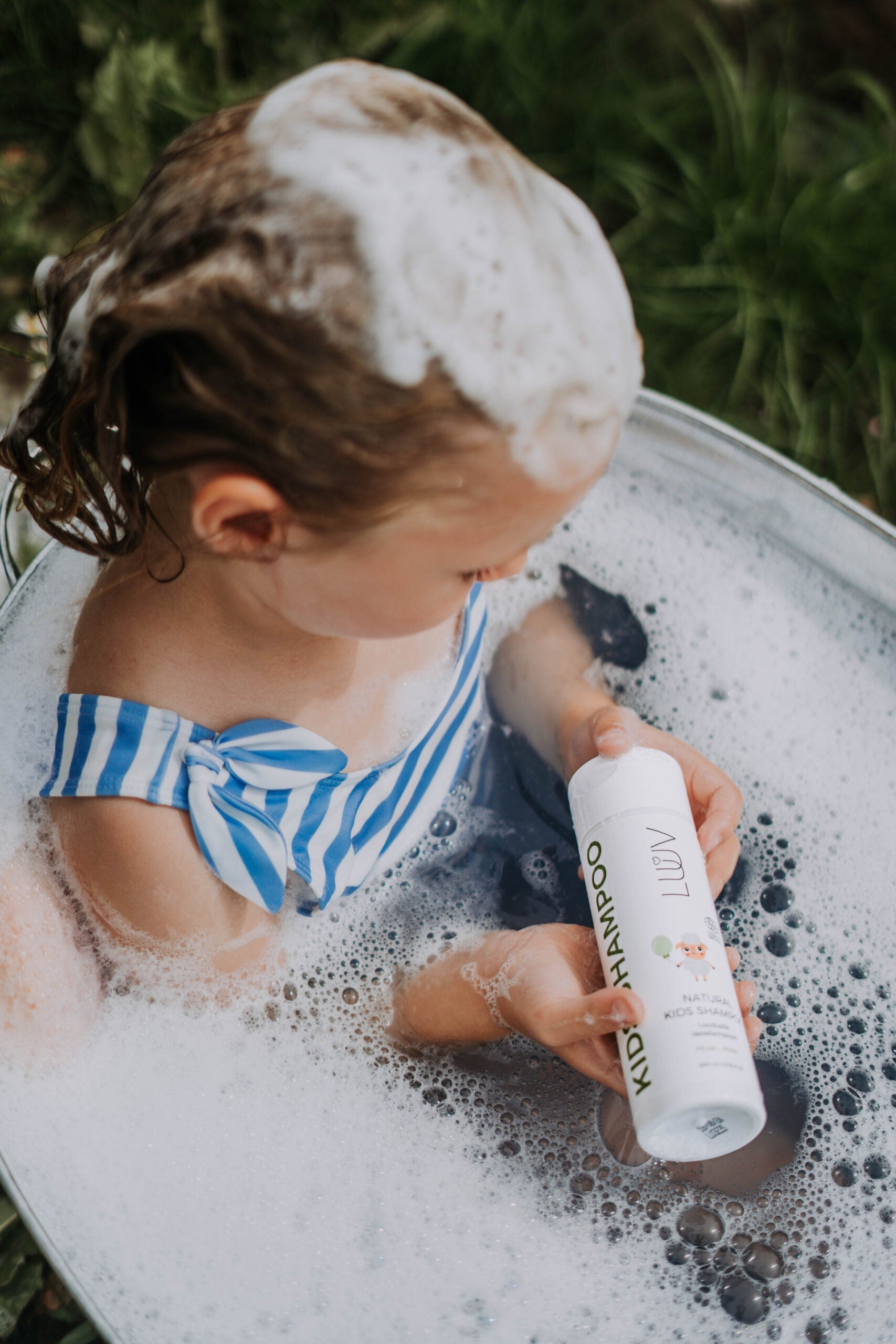 playful luuv natural pear kids shampoo bottle with a fresh pear on a sunny bathroom windowsill