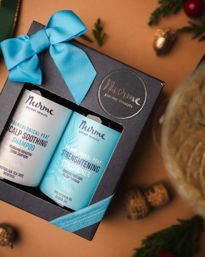 bold presentation of a peat shampoo and conditioner gift set for sensitive scalps on a dark slate background