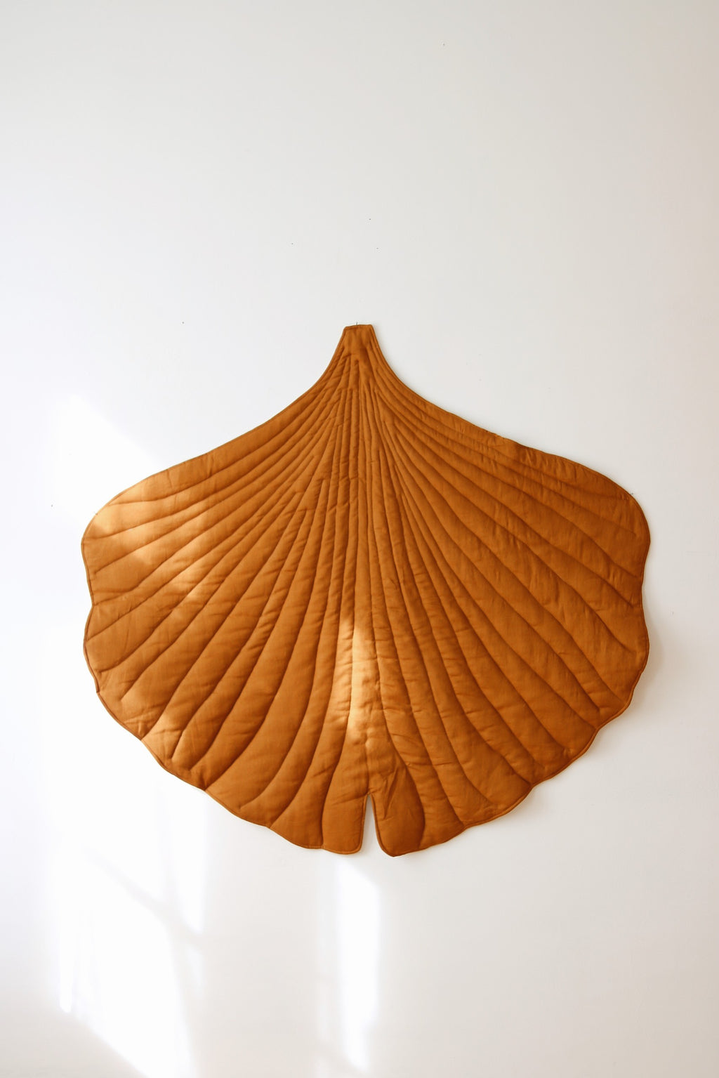 soft caramel ginkgo leaf playmat on a nursery floor in warm morning light