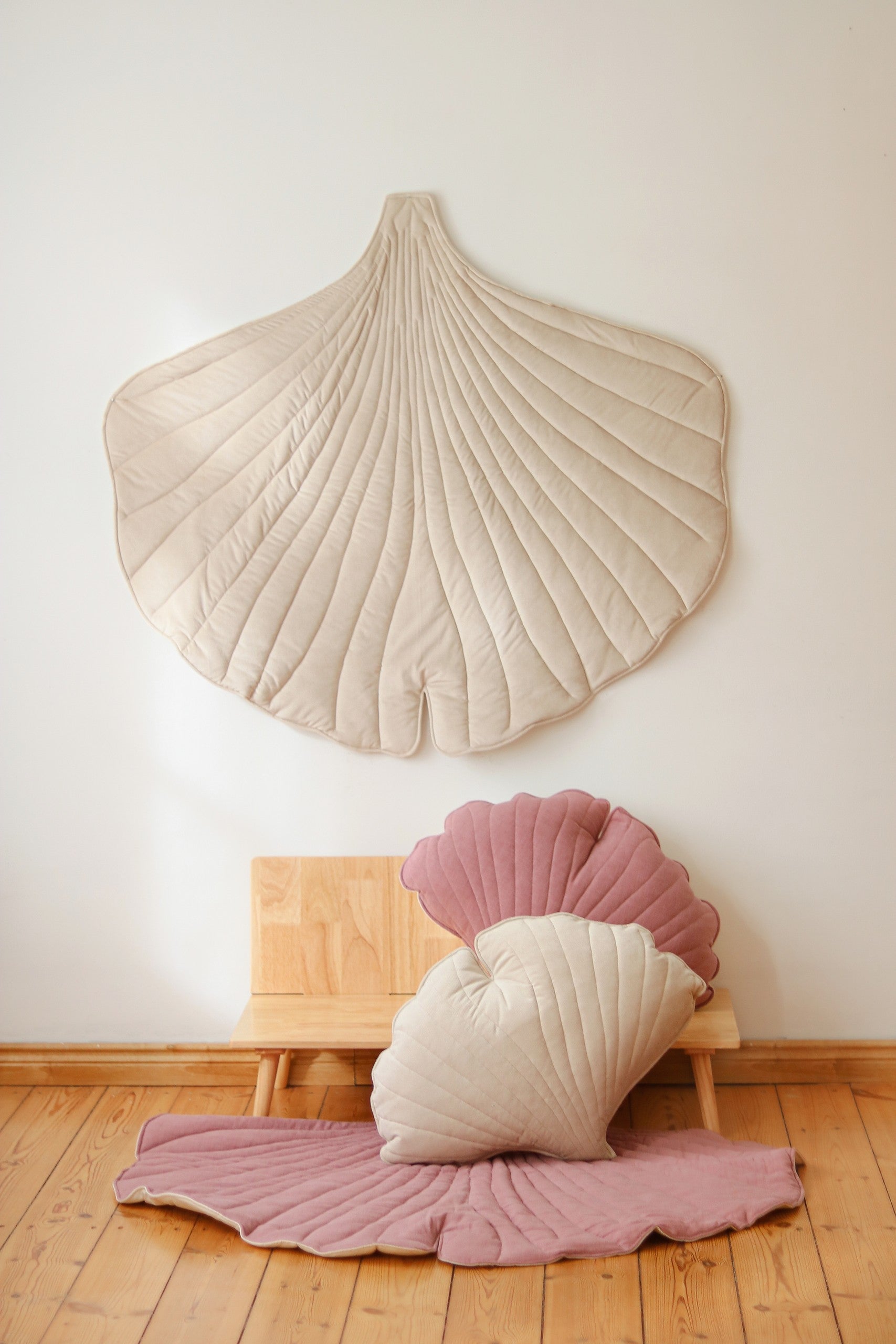 bold ginkgo leaf playmat in cream on a dark floor, showcasing its large size and plush texture
