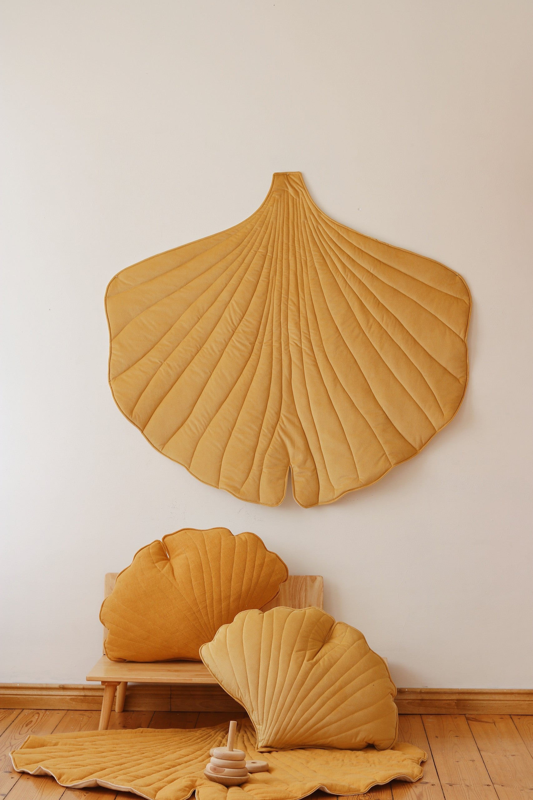 a playful yellow ginkgo leaf playmat with a toddler giggling on the soft velvet surface