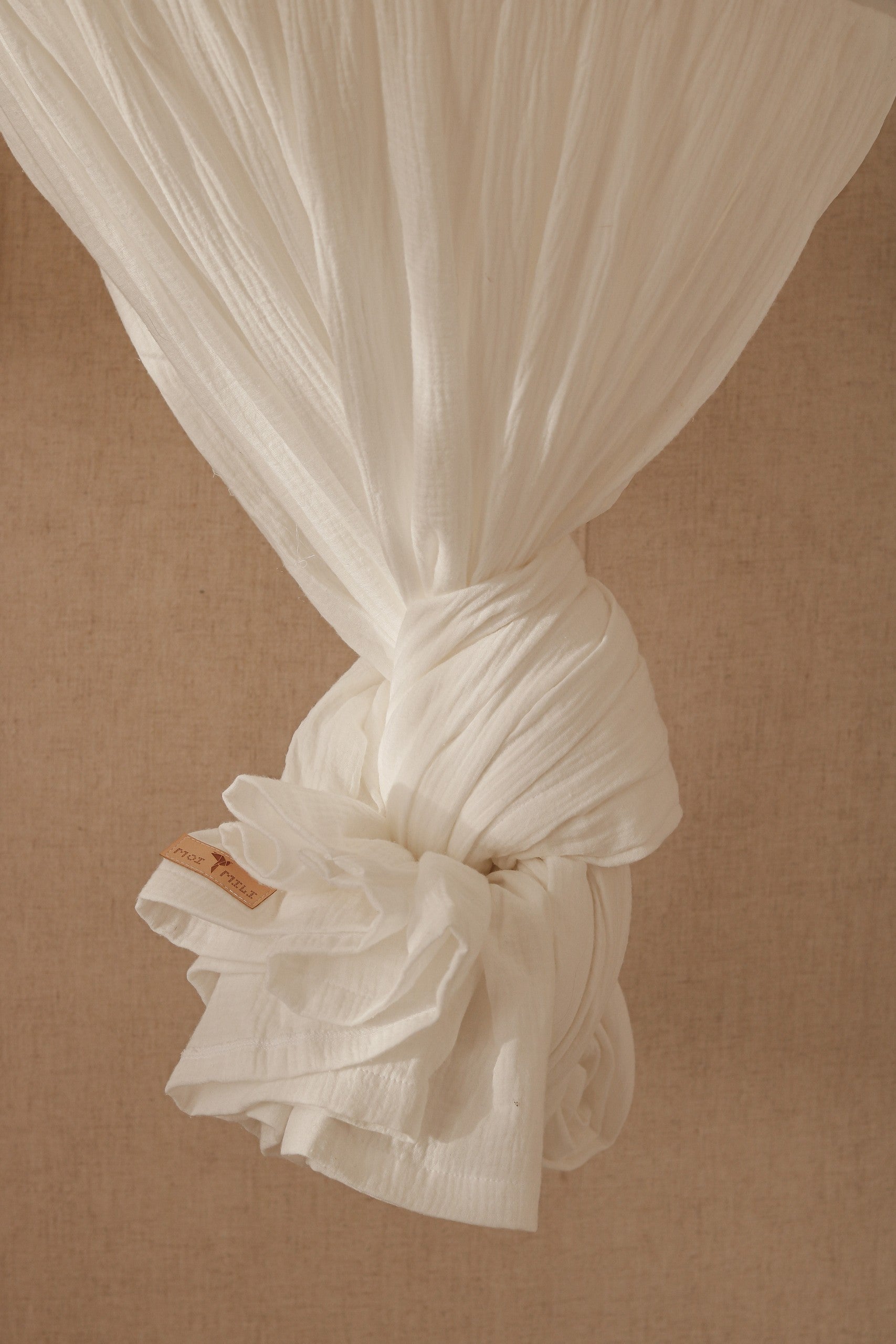 organic cotton cream canopy hanging over a bed with soft natural light, ready for cozy naps or play