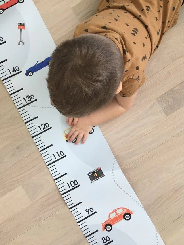 playful retro cars growth chart on a childs wall with warm morning light
