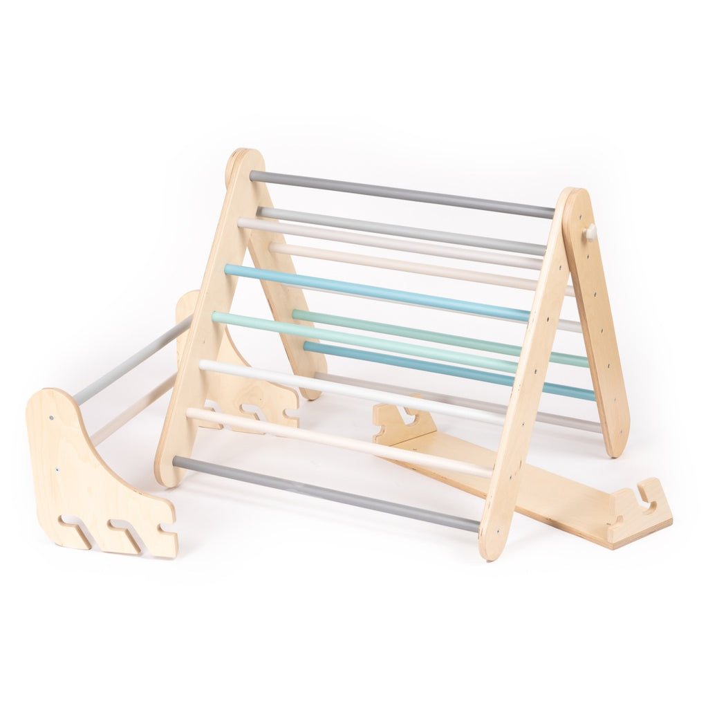 a child's hand gripping the pastel birch rung of a compact pikler triangle and swedish wall set