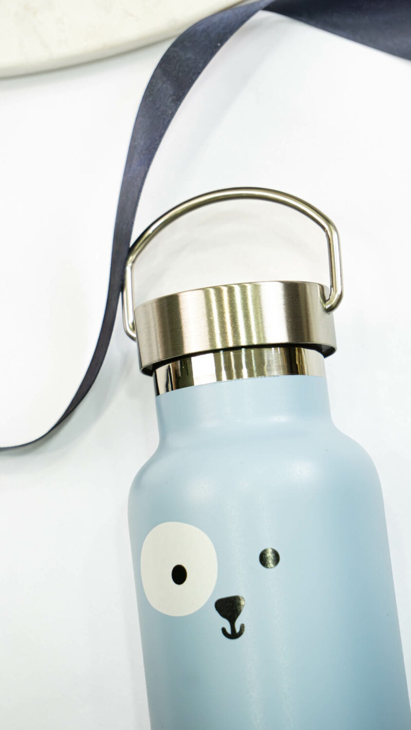 a soft blue puppy thermos for kids with a gentle smile, held in small hands