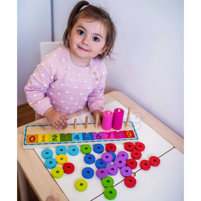 a child's hand placing a green counting puzzle piece on a sunlit wooden board