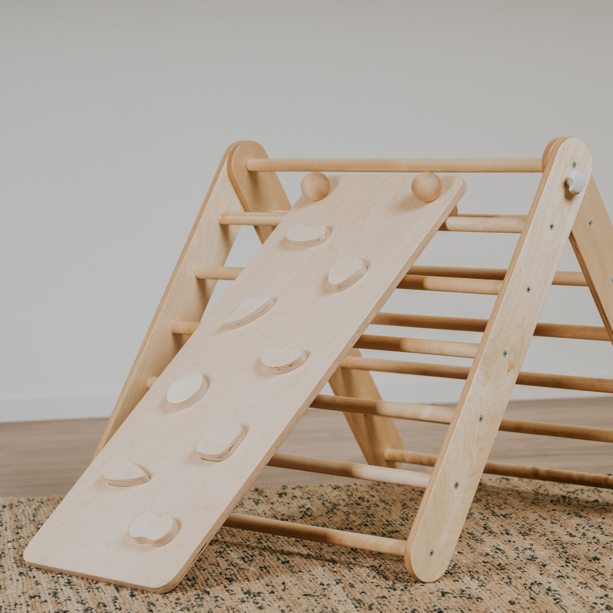 a minimalist birch plywood climbing ramp with textured rock holds, elegantly integrated into a modern interior