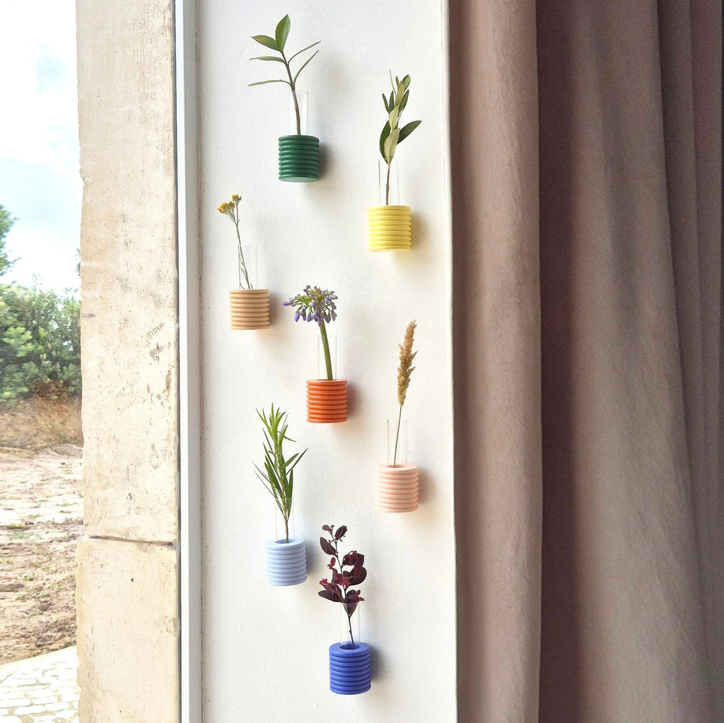 soft blue handmade beech wood wall vase holding a single dried flower in warm morning light