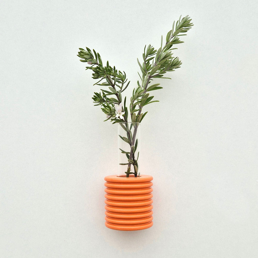 bold orange handcrafted wood wall vase with a single vibrant flower on a clean white background