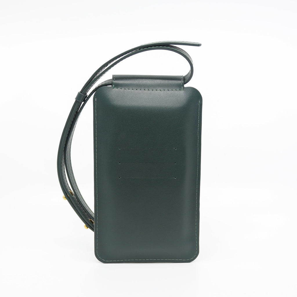 a soft forest green leather crossbody phone bag held gently in natural light, showing its smooth texture and elegant sam browne button