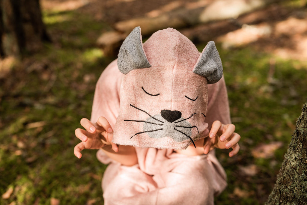 toddler in a soft bamboo poncho, side profile showing the cozy hood and pockets in gentle morning light