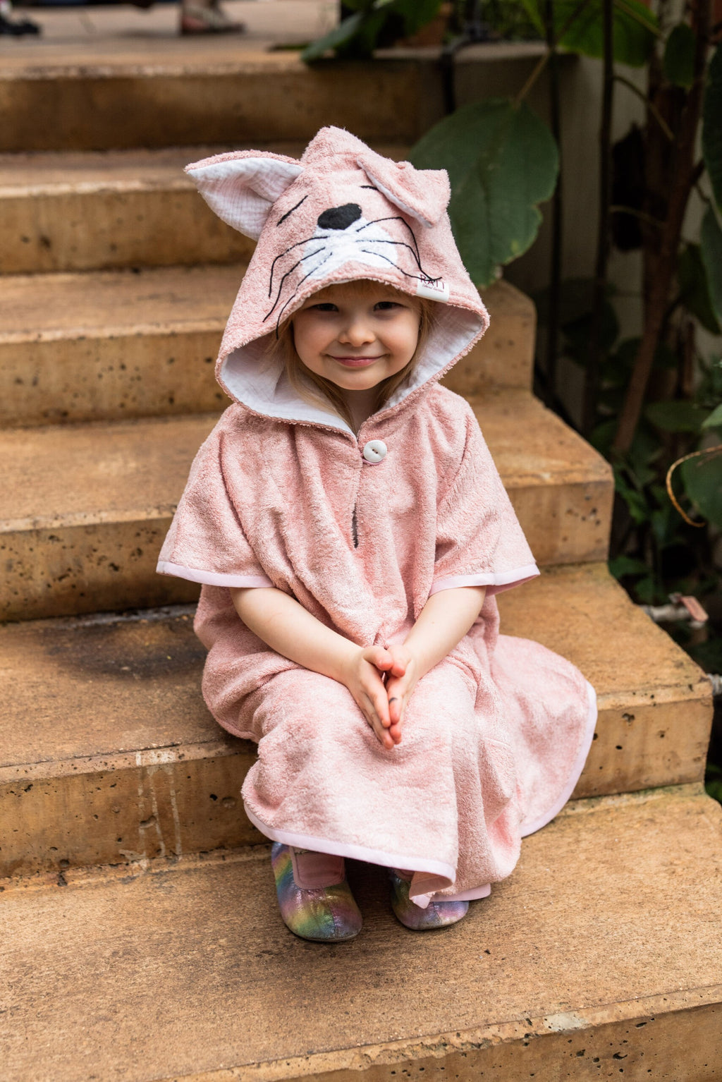 confident toddler in a bold bamboo poncho with a hood and pockets, standing strong