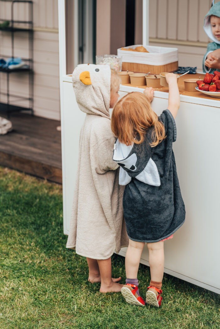 a toddler wrapped in a soft bamboo wolf poncho, cozy and dry after a swim