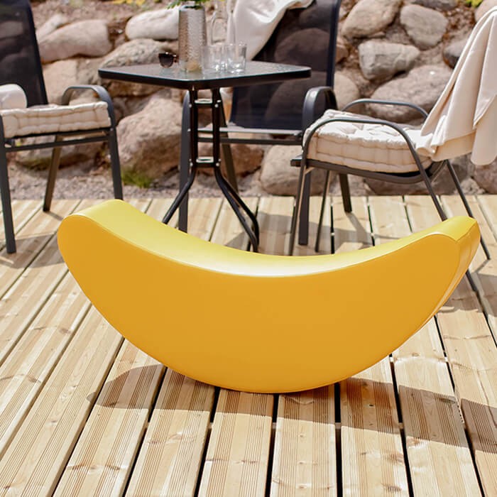 child laughing as they rock on a bright yellow banana soft play toy