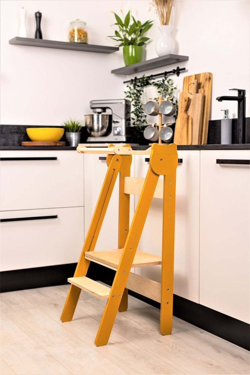 foldable baltic birch step stool for kids folded flat against a modern kitchen wall
