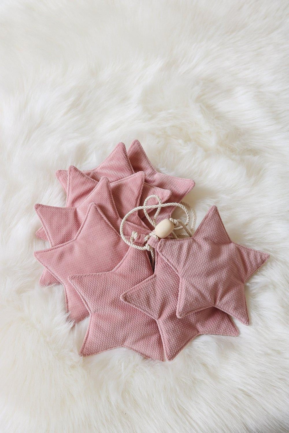 soft pink velvet star garland with wooden beads on a cozy nursery wall