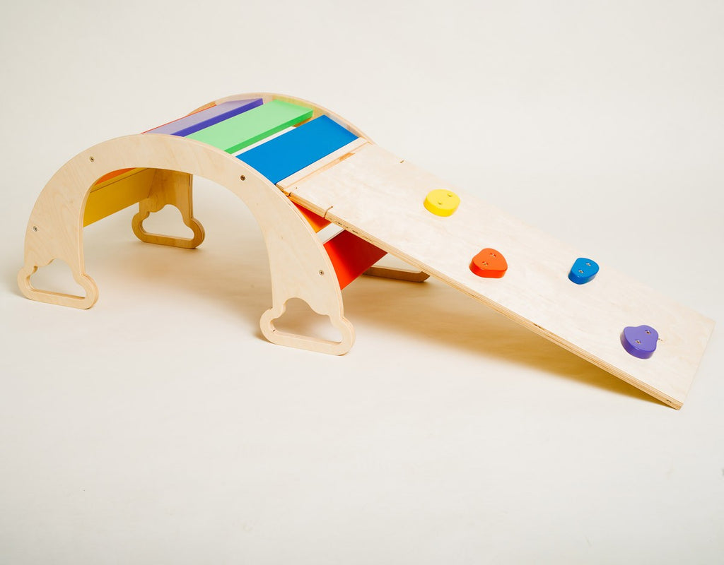 bold rainbow ramp with climbing rocks on a vibrant playroom floor