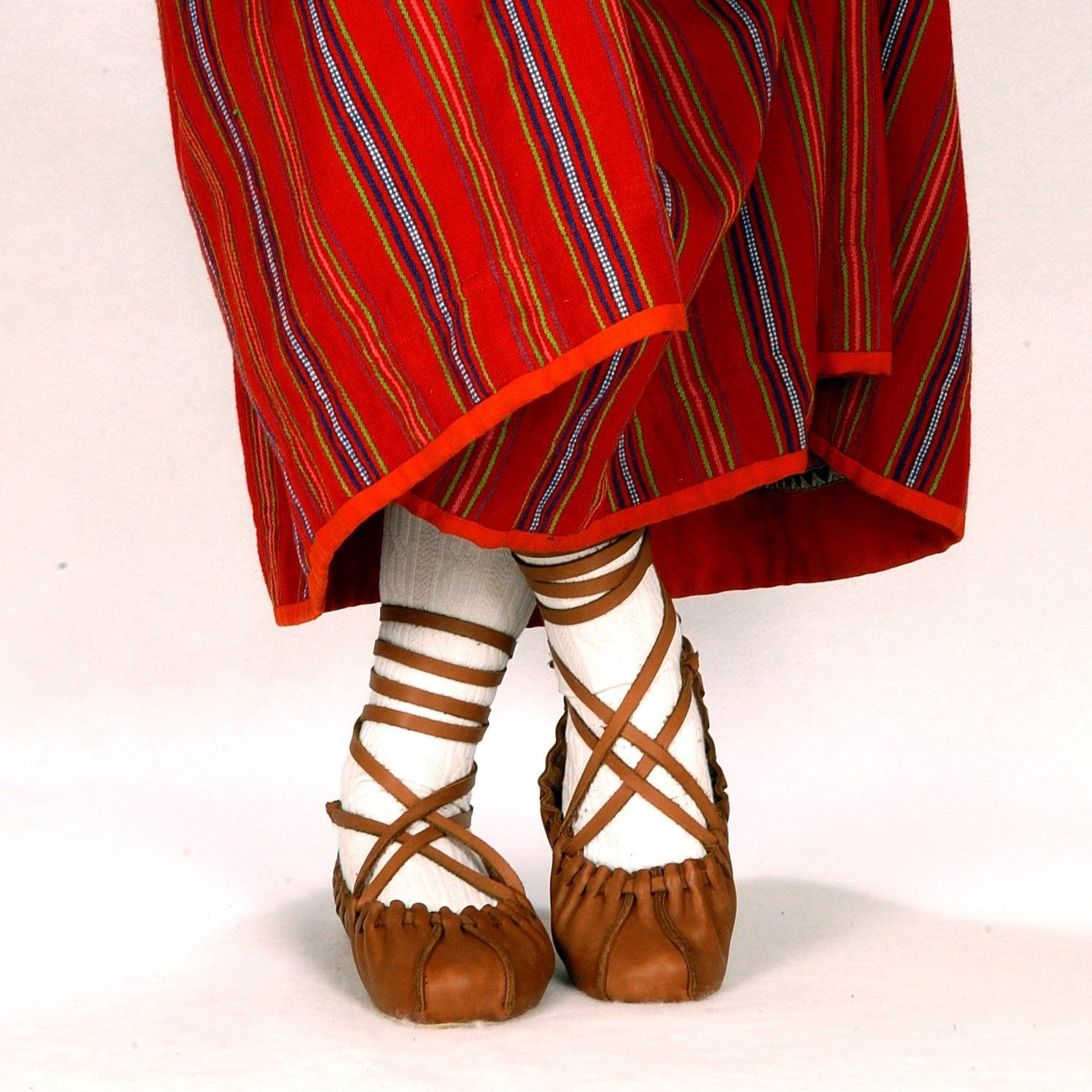 a close-up side view of soft leather dancing shoes with tied laces, resting on a cozy textile bag