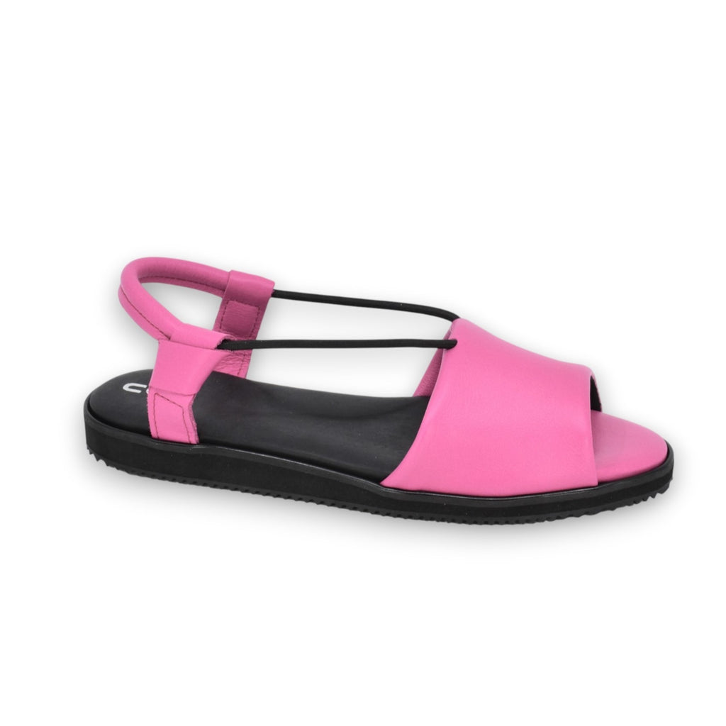a playful close-up of vibrant fuchsia toku berlin sandals on a sunlit summer patio