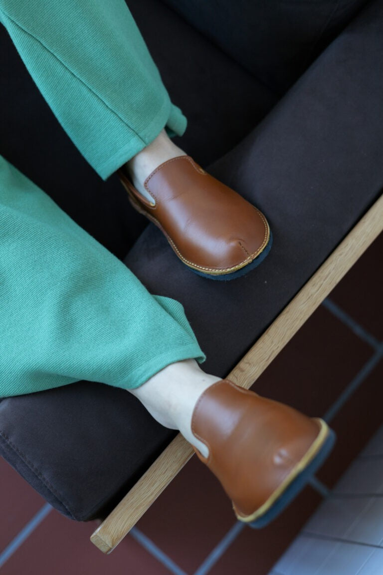 confident close-up of ocre leather toku london loafers on a dark textured surface